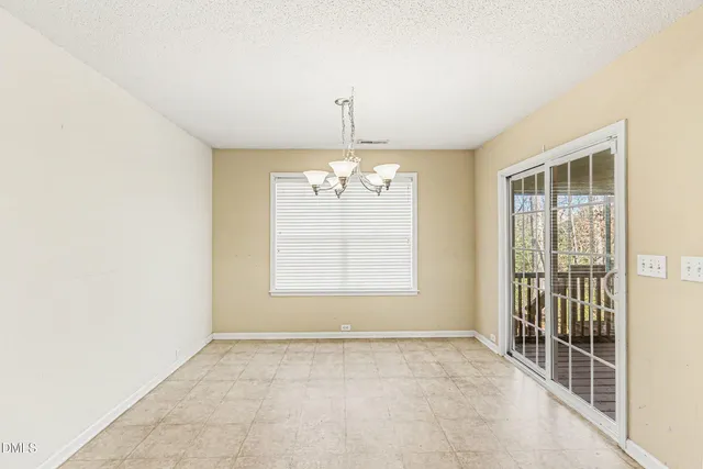 an empty room with chandelier fan and windows