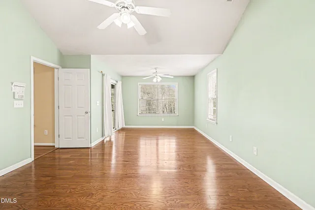 a view of an empty room with wooden floor and a window