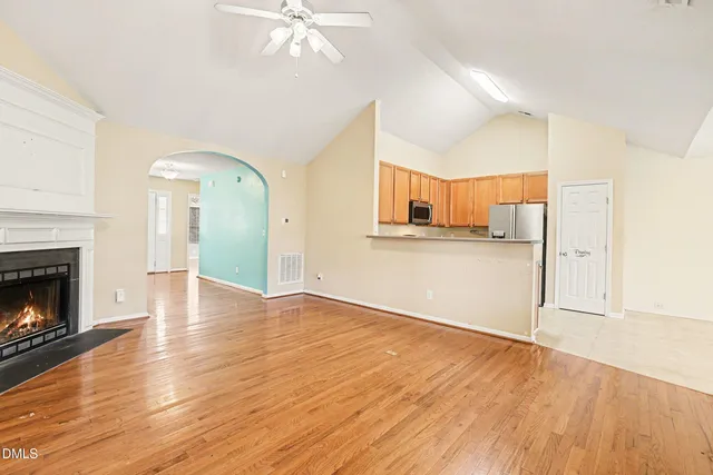 a view of a kitchen and an empty room with wooden floor