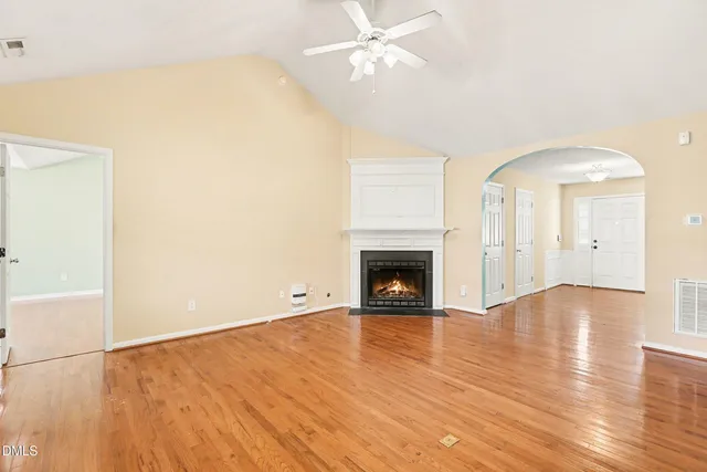 an empty room with wooden floor fireplace and ceiling fan