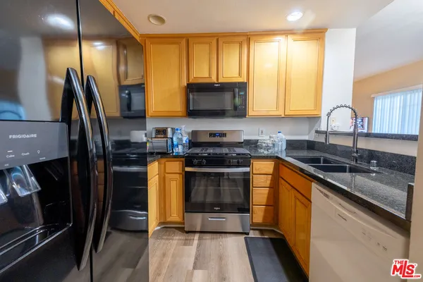 a kitchen with stainless steel appliances a stove a sink a microwave a refrigerator and cabinets