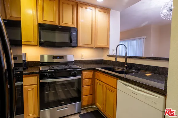 a kitchen with stainless steel appliances granite countertop a sink stove and microwave