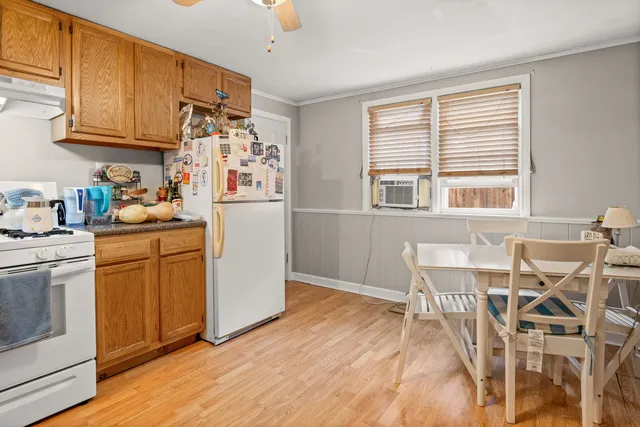 a kitchen with stainless steel appliances granite countertop a stove a refrigerator a dining table and chairs with wooden floor