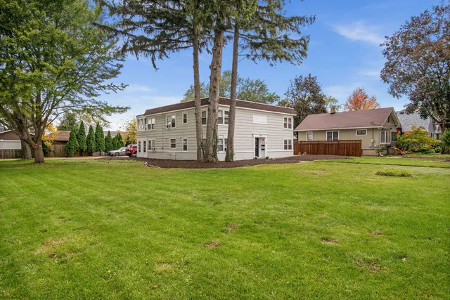 a view of a house with a big yard and large trees
