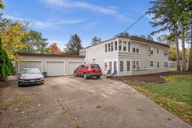 a view of a house with a cars park side of a road