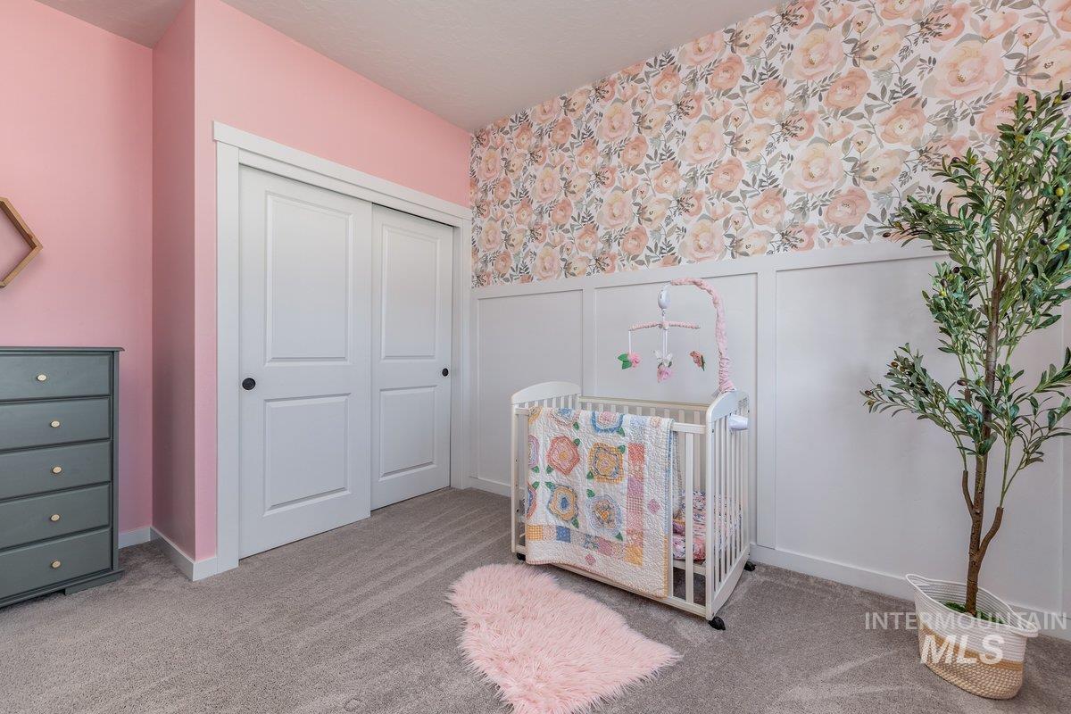 1380 West Chilitna Street Meridian, ID 83642 - Photo 31 of 50 Bedroom featuring a paneled accent wall with floral-patterned wallpaper, light pink painted walls, and gray carpet flooring
