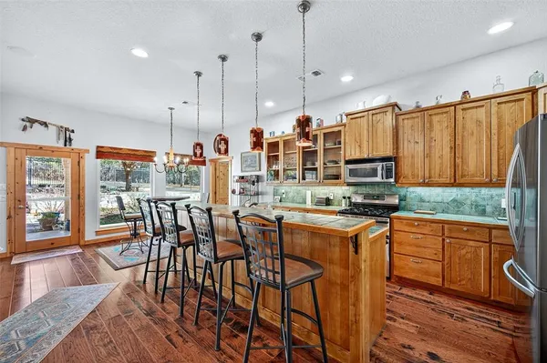 a kitchen with stainless steel appliances kitchen island granite countertop a table chairs and a refrigerator