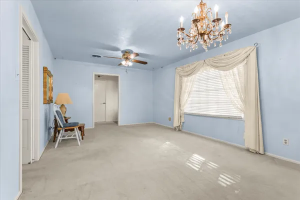 an empty room with closet and a chandelier fan