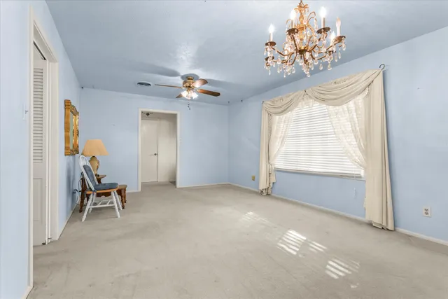 an empty room with closet and a chandelier fan