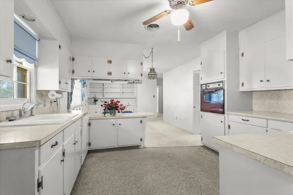 an empty room with windows and chandelier fan