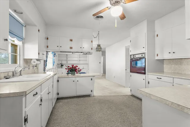 an empty room with windows and chandelier fan
