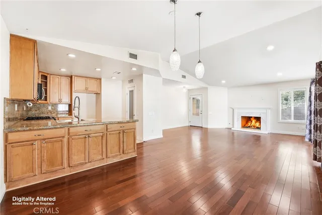 a large kitchen with kitchen island a stove a sink a refrigerator and a wooden floor