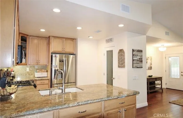 a kitchen with stainless steel appliances granite countertop a sink refrigerator and cabinets
