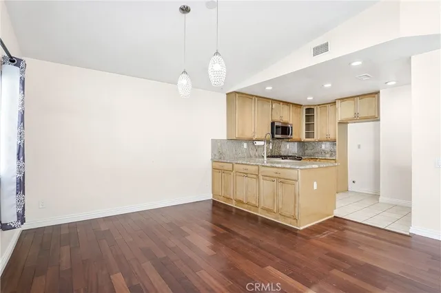 a kitchen with stainless steel appliances granite countertop a refrigerator a sink dishwasher a stove and white countertops with wooden floor