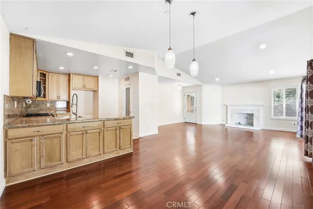 a open kitchen with granite countertop a stove top oven a sink white cabinets and wooden floor