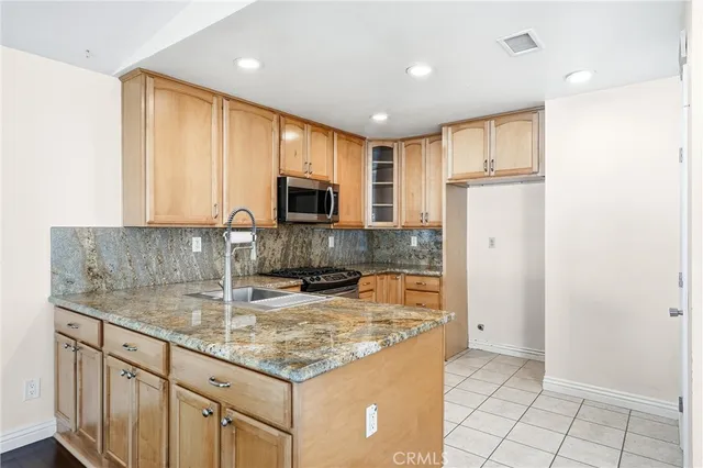 a kitchen with stainless steel appliances granite countertop a refrigerator a stove a sink and a microwave