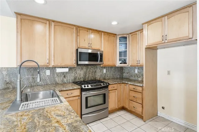 a kitchen with granite countertop a stove a sink and a microwave