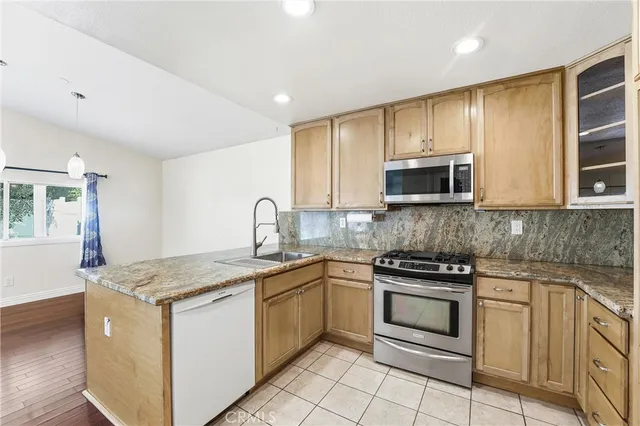 a kitchen with stainless steel appliances granite countertop a stove a sink and a microwave