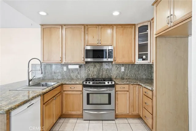 a kitchen with stainless steel appliances granite countertop white cabinets stove and a sink