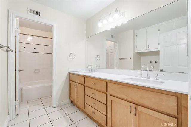 a spacious bathroom with a double vanity sink mirror and bathtub
