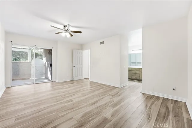 a view of an empty room with wooden floor and a cabinet