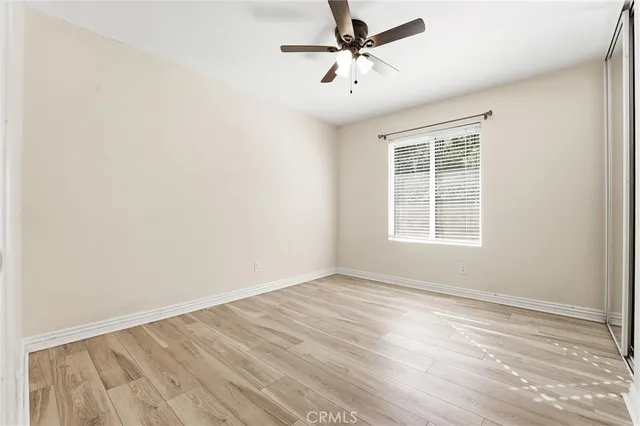 an empty room with wooden floor fan and windows