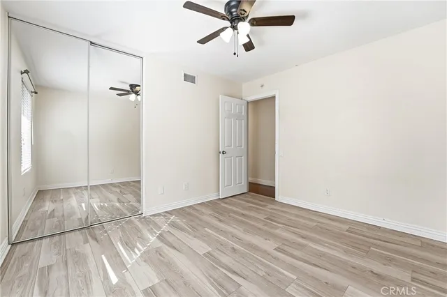 an empty room with wooden floor chandelier fan and windows