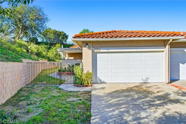 a view of a house with a small yard and a large tree