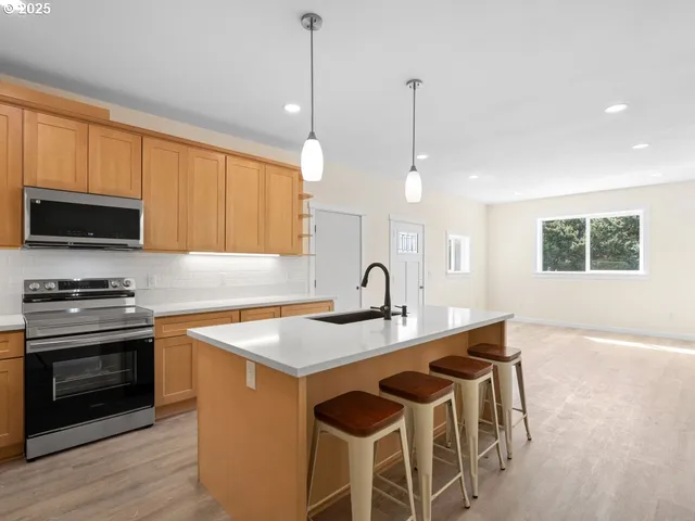 a kitchen with stainless steel appliances granite countertop a sink a microwave a stove and a wooden floors