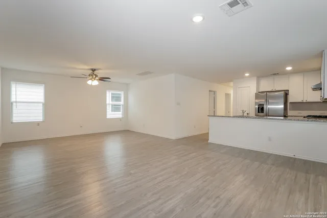 an empty room with wooden floor and windows