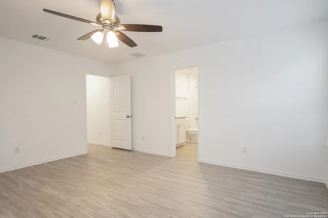 an empty room with wooden floor fan and windows