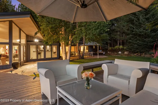 a view of a patio with couches table and chairs under an umbrella