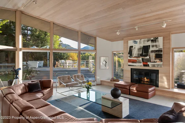a living room with furniture a fireplace and floor to ceiling windows