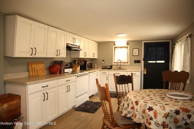 a kitchen with stainless steel appliances kitchen island granite countertop a refrigerator a stove a sink dishwasher and white cabinets with wooden floor