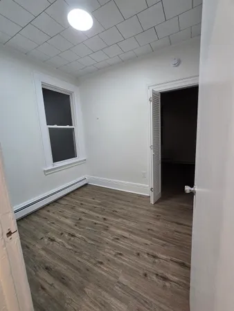 a view of an empty room with wooden floor and closet