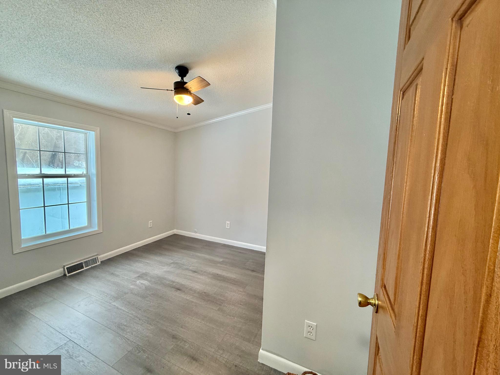 194 Jacobstown New Egypt Road, Unit 2 Wrightstown, NJ 08562 - Photo 13 of 17 an empty room with wooden floor chandelier fan and windows