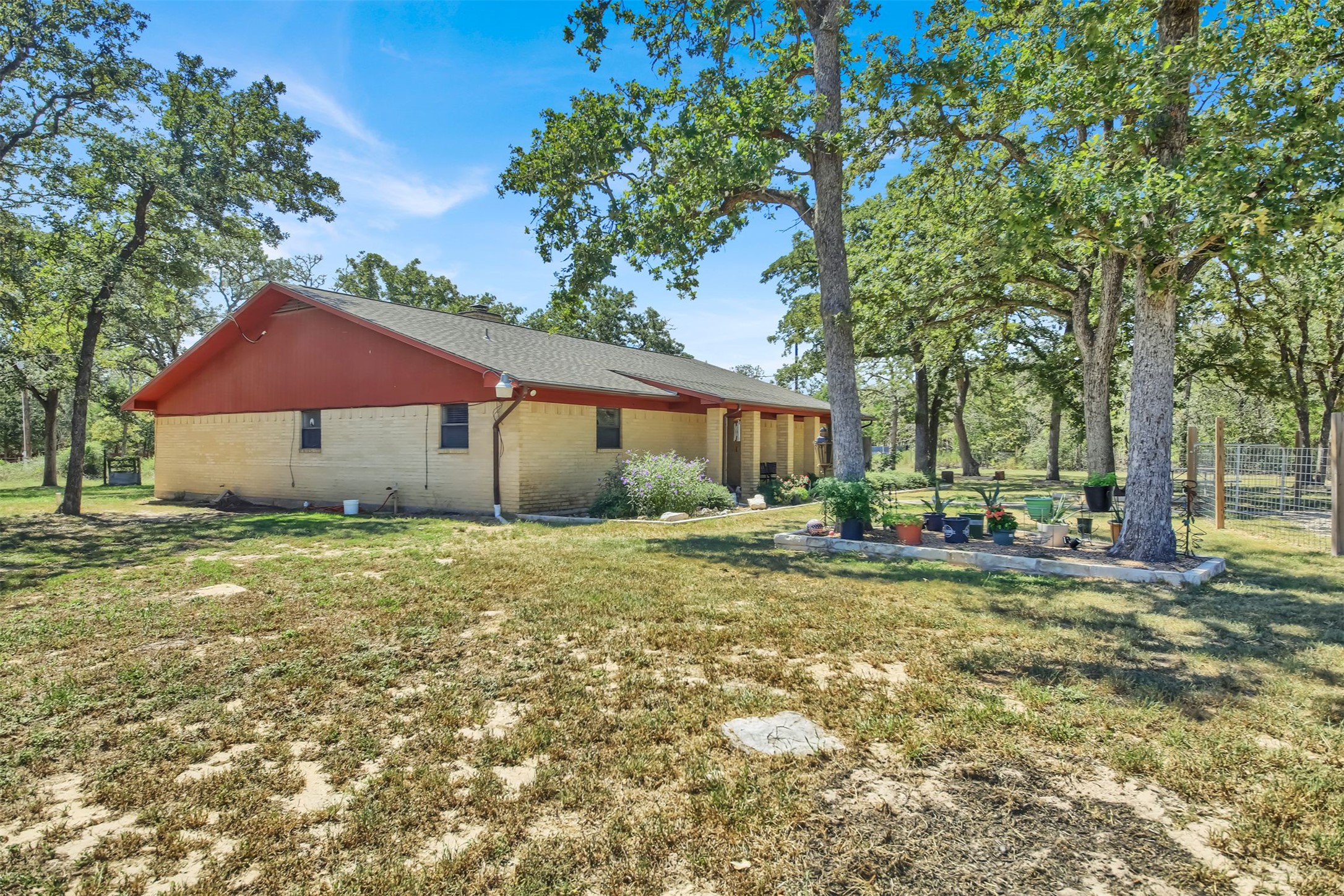 191 Jordan Lane Elgin, TX 78621 - Photo 25 of 29 Mature shade trees surround a single-story brick home on an expansive grassy lot.