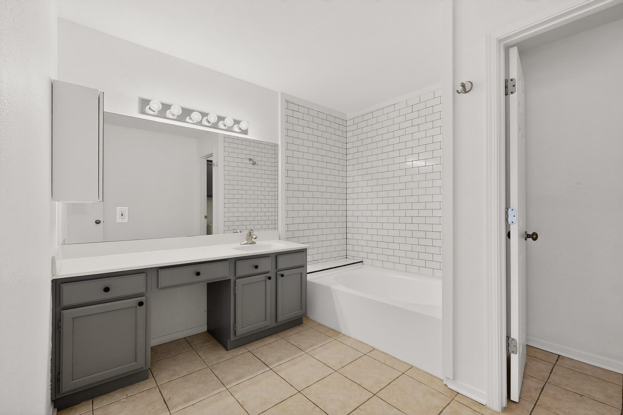 2450 Wickersham Lane, Unit 904 Austin, TX 78741 - Photo 20 of 35 a bathroom with a tub sink and mirror