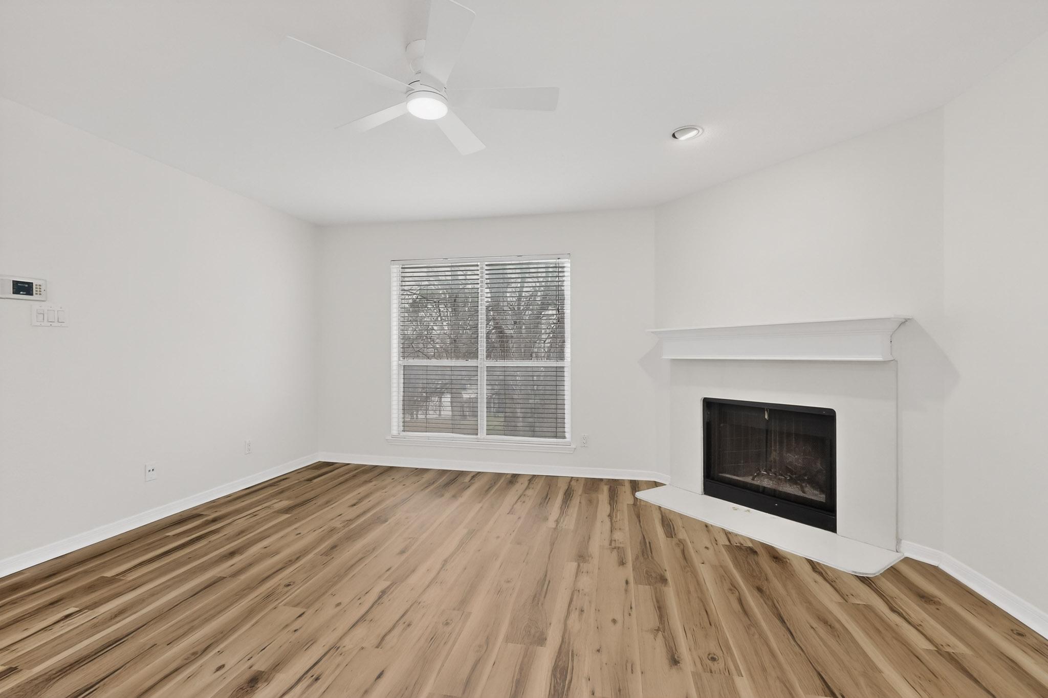 2450 Wickersham Lane, Unit 904 Austin, TX 78741 - Photo 5 of 35 a view of an empty room with wooden floor fireplace and a window