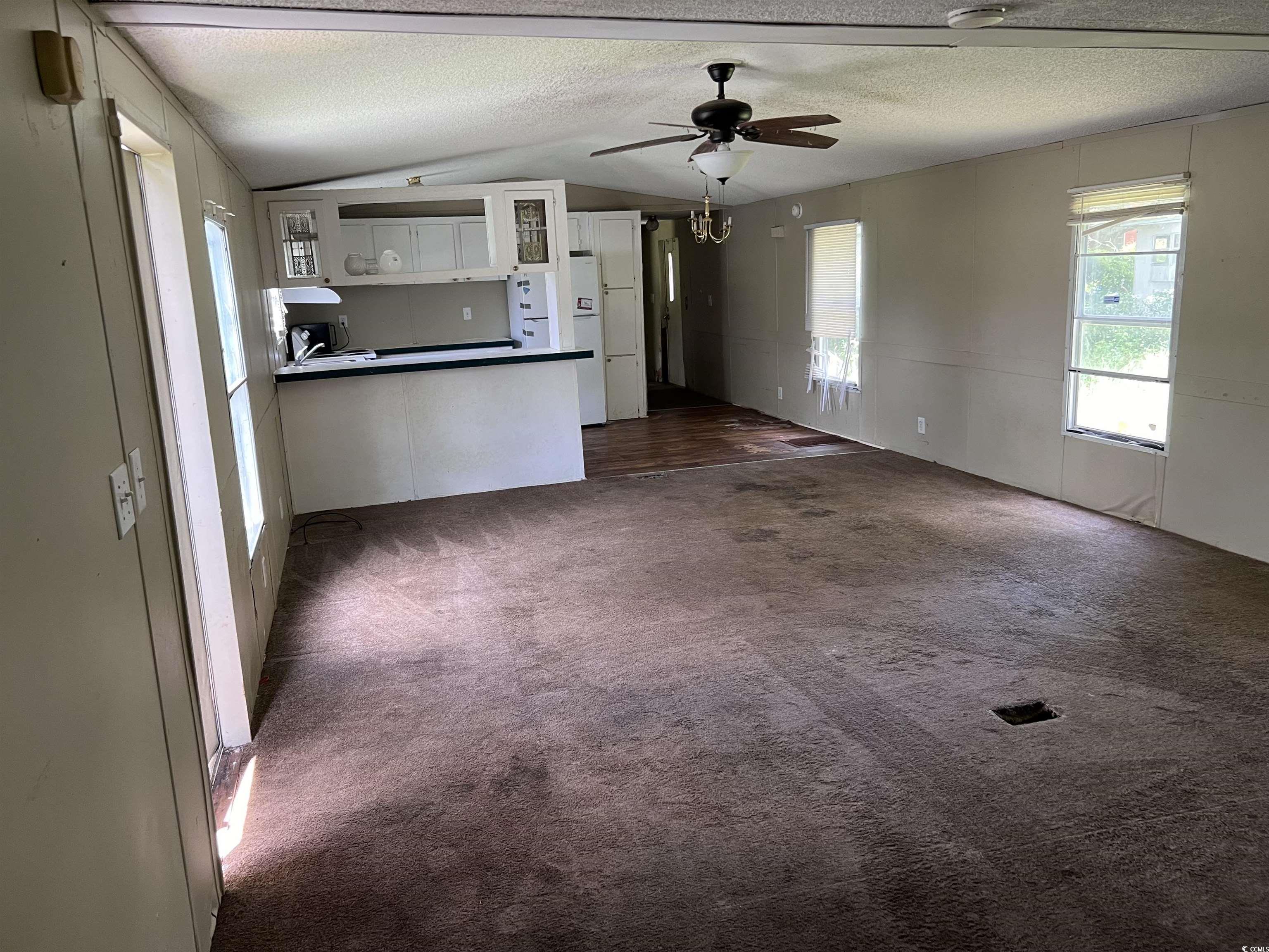 1118 Decatur Street Northeast Orangeburg, SC 29118 - Photo 2 of 14 Unfurnished living room with a textured ceiling, vaulted ceiling, dark colored carpet, and ceiling fan
