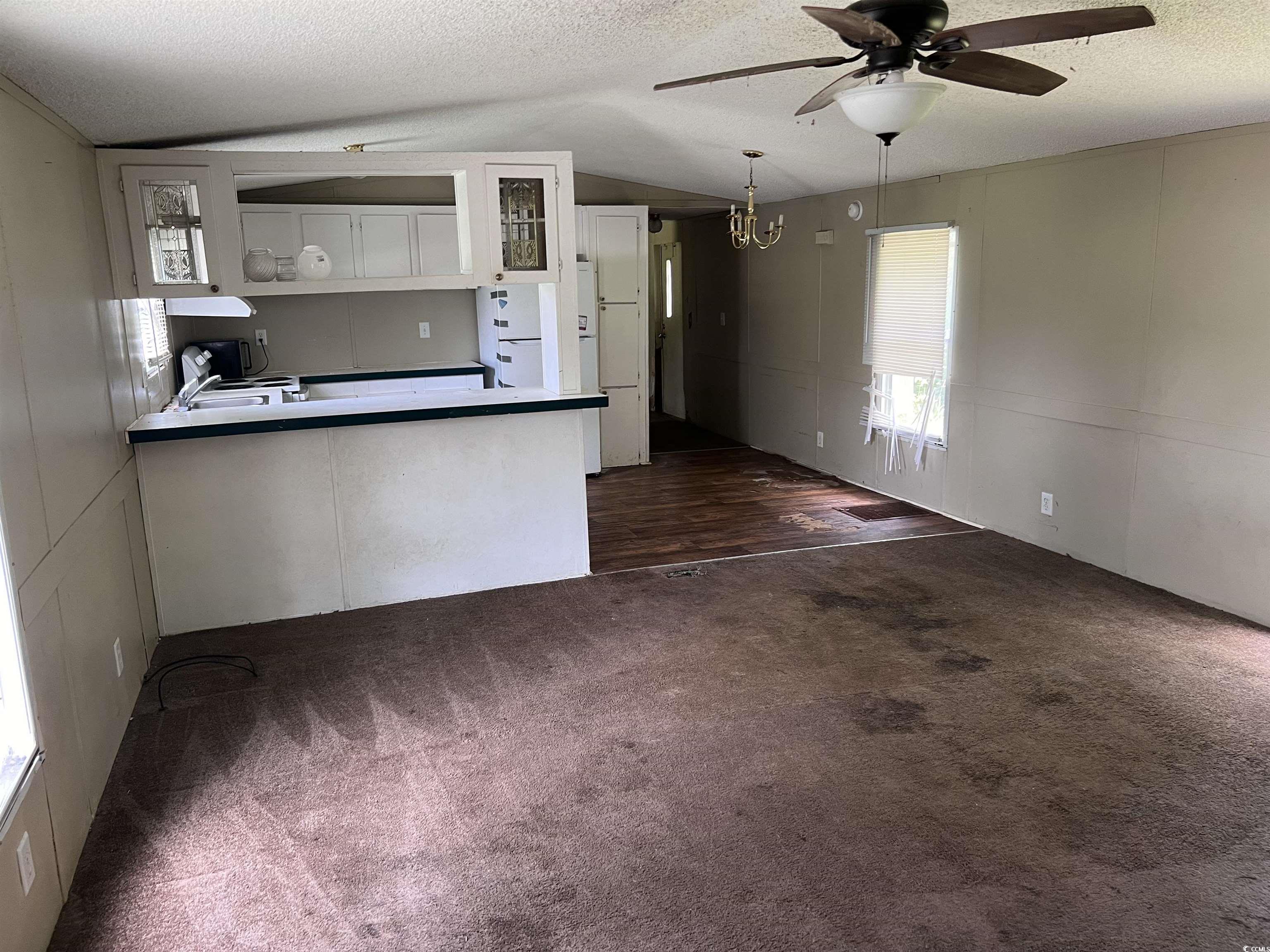 1118 Decatur Street Northeast Orangeburg, SC 29118 - Photo 4 of 14 Kitchen with a textured ceiling, vaulted ceiling, white cabinets, a peninsula, and dark colored carpet