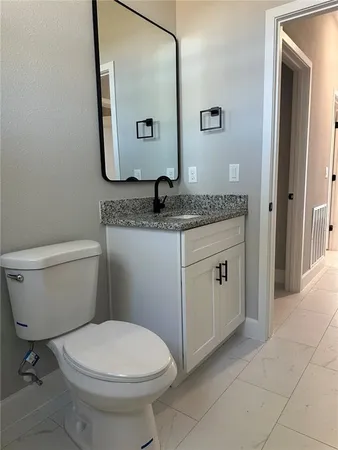 a bathroom with a granite countertop toilet sink and mirror