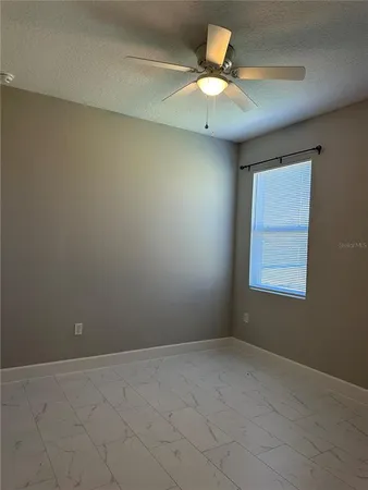 an empty room with a window and a ceiling fan