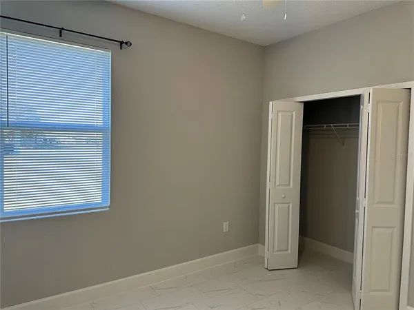 a view of an empty room with closet and a window