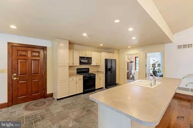 a large kitchen with stainless steel appliances kitchen island granite countertop a refrigerator oven a sink a dining table and chairs with wooden floor