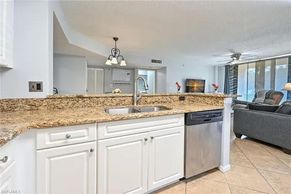 a kitchen with granite countertop a sink and white cabinets