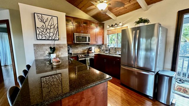 a kitchen with stainless steel appliances granite countertop a refrigerator a stove and a sink with wooden floor