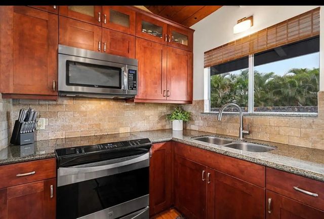 a kitchen with granite countertop a sink stove and microwave