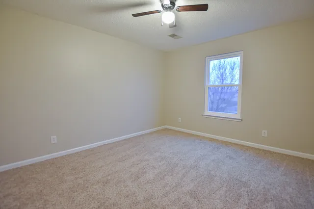 an empty room with windows and fan
