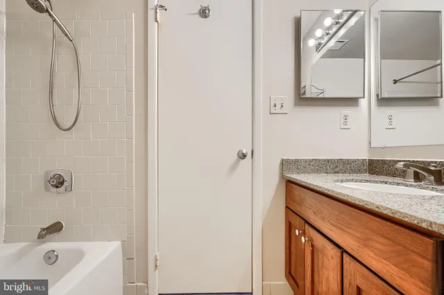 a bathroom with a granite countertop sink a mirror and shower